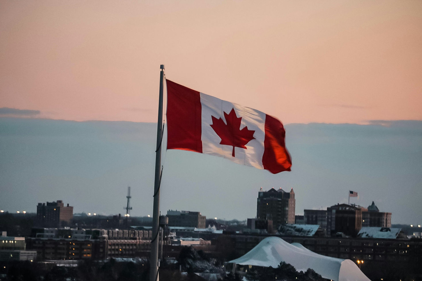 Wapperende Canadese vlag boven een stadsgezicht bij avondlicht, archieffoto gepubliceerd in februari 2019.